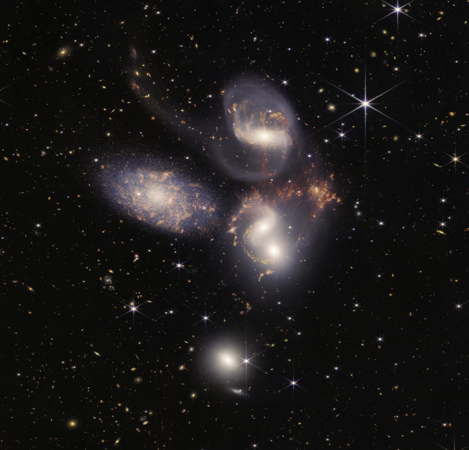 Stephan's Quintet in near- and mid-infrared combined: five galaxies, four of them tangled together, with orange dust and gas between them, against a field of distant galaxies